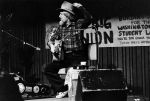 (32379) Utah Phillips, Holding his Hat and Guitar During a Performance, Washington, circa 1980